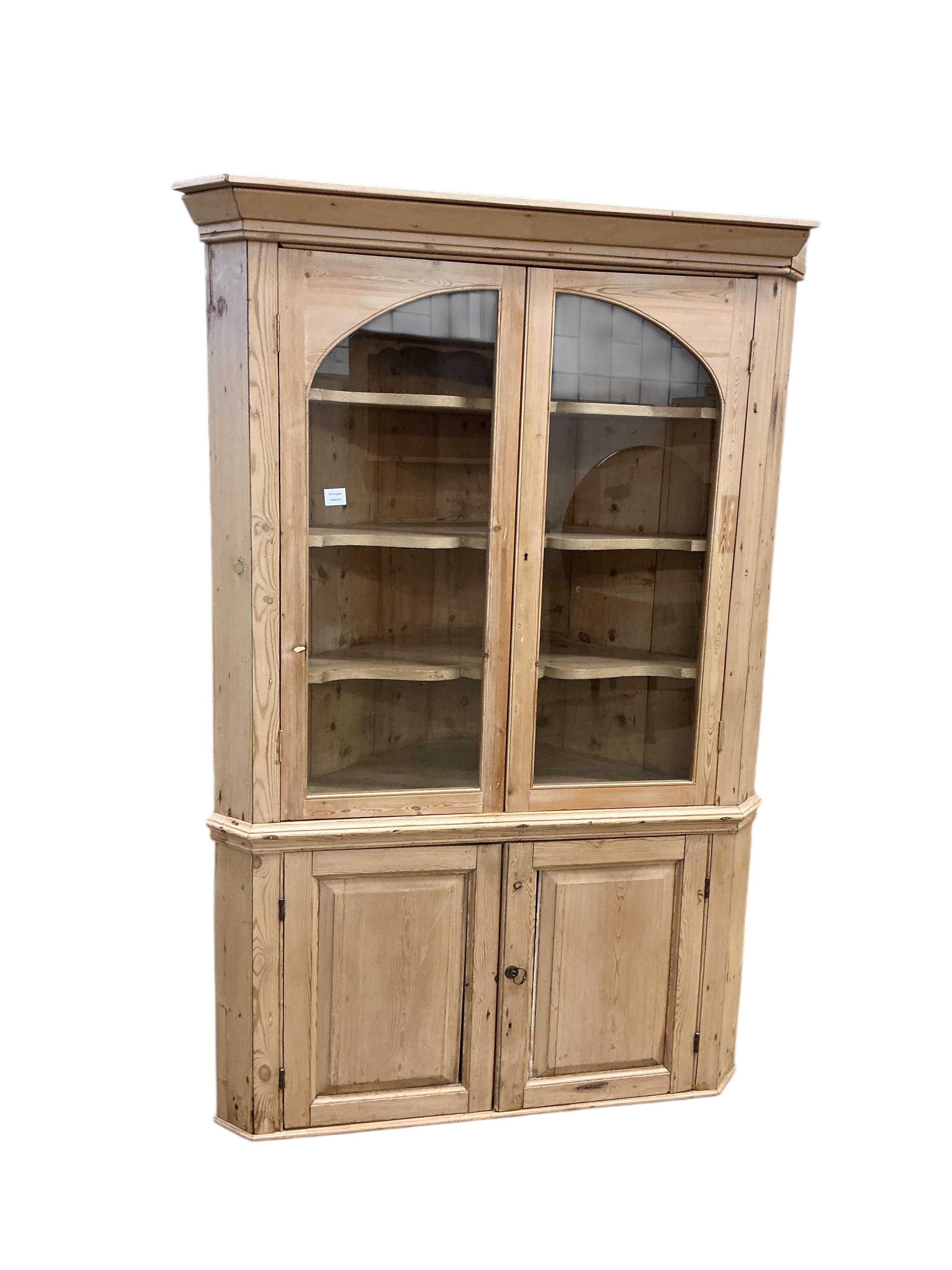 An early 19th century glazed pine standing corner cupboard, width 126cm, depth 62cm, height 191cm